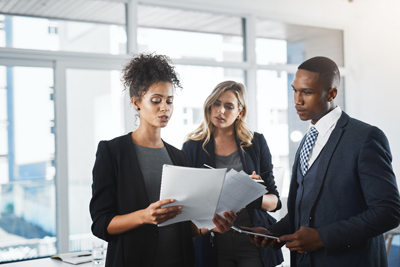three professionals discussing documents in an office setting