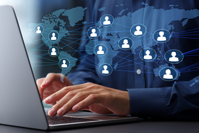 person using laptop with world map and network connections representing global communication and online interaction
