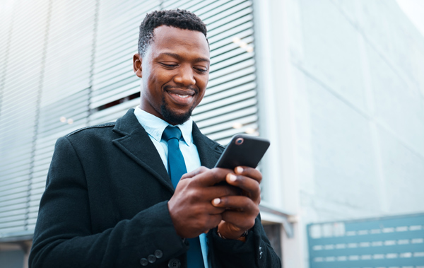 smiling man in a black coat using a smartphone outdoors urban setting modern architecture