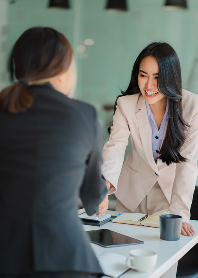 Two business professionals shaking hands in a modern office setting showcasing a successful meeting and collaboration